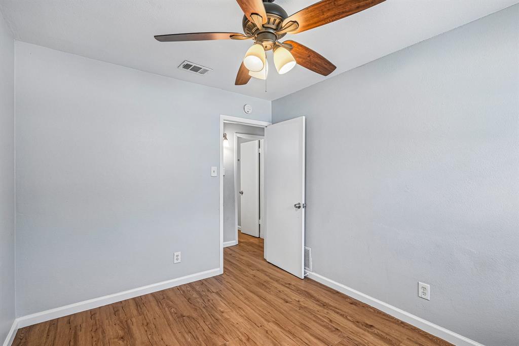 Wood-finish flooring, light blue wall paint, and a ceiling fan with integrated lighting