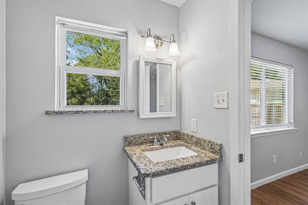 Vanity with granite-style countertop, white cabinetry, and undermount sink