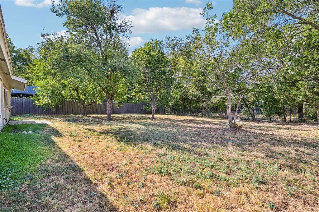 Expansive grassy area, mature trees, and privacy fencing
