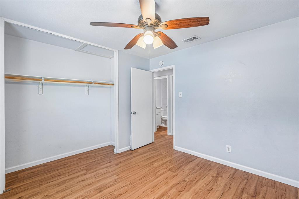 Wood-finish flooring, light blue wall paint, white trim, and a ceiling fan with integrated lighting