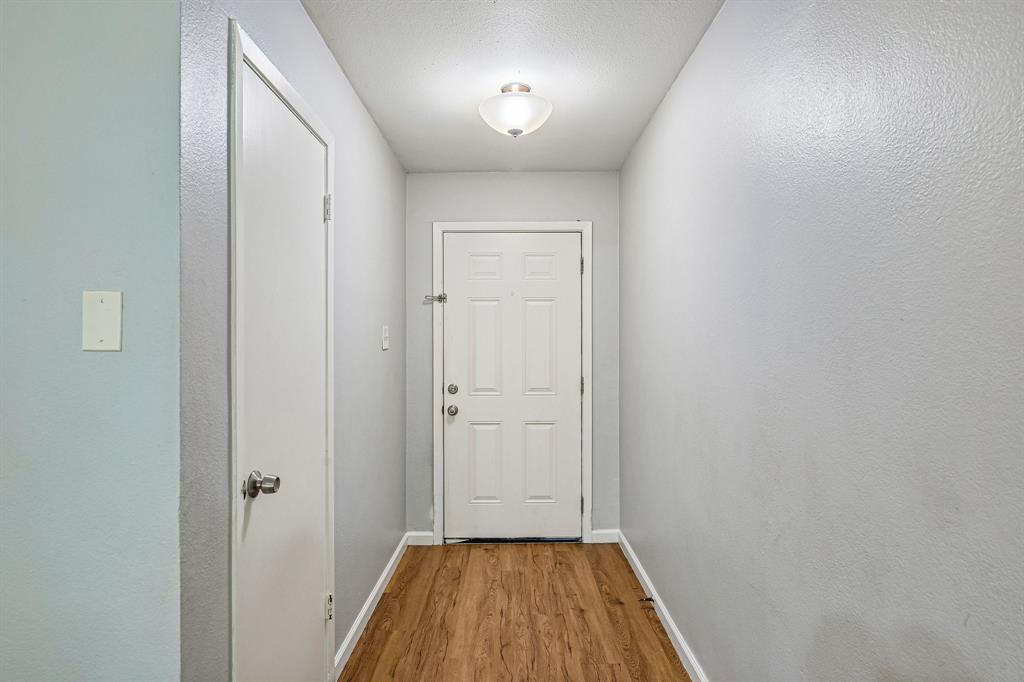 Entryway featuring wood-finish flooring, a white panel door, and a flush mount light fixture
