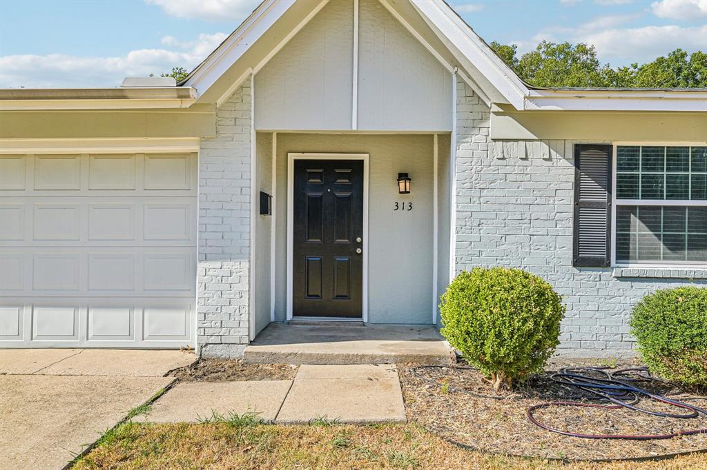 Painted brick exterior with a paneled garage door, black front door, and exterior sconce lighting