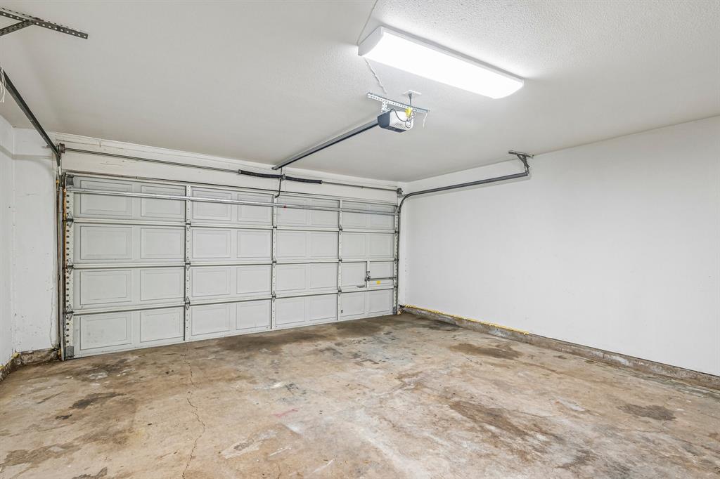 Attached garage with a panel-style door, concrete flooring, and overhead lighting
