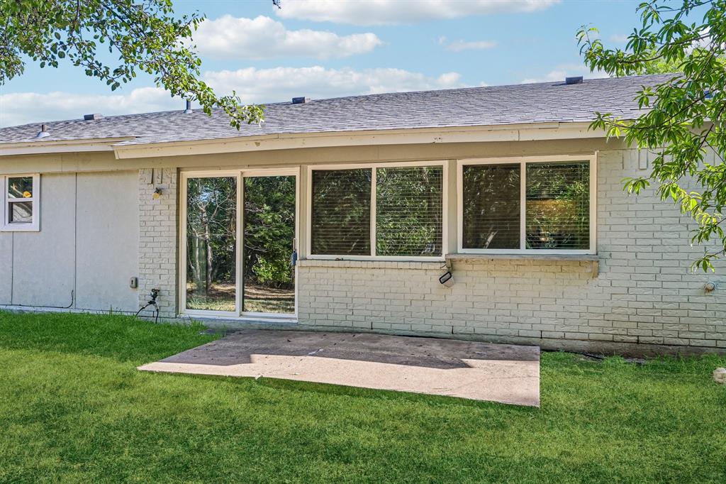 Back exterior featuring a concrete patio, sliding glass door, and multiple windows