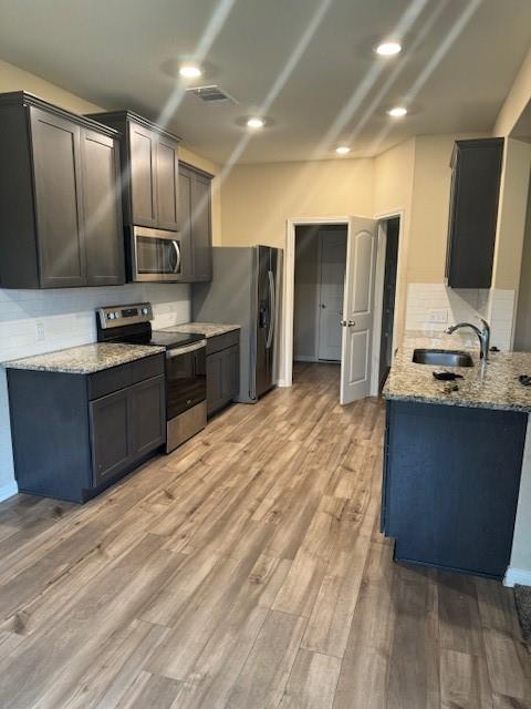 Modern kitchen featuring wood-finish flooring, dark cabinetry, and light-colored countertops