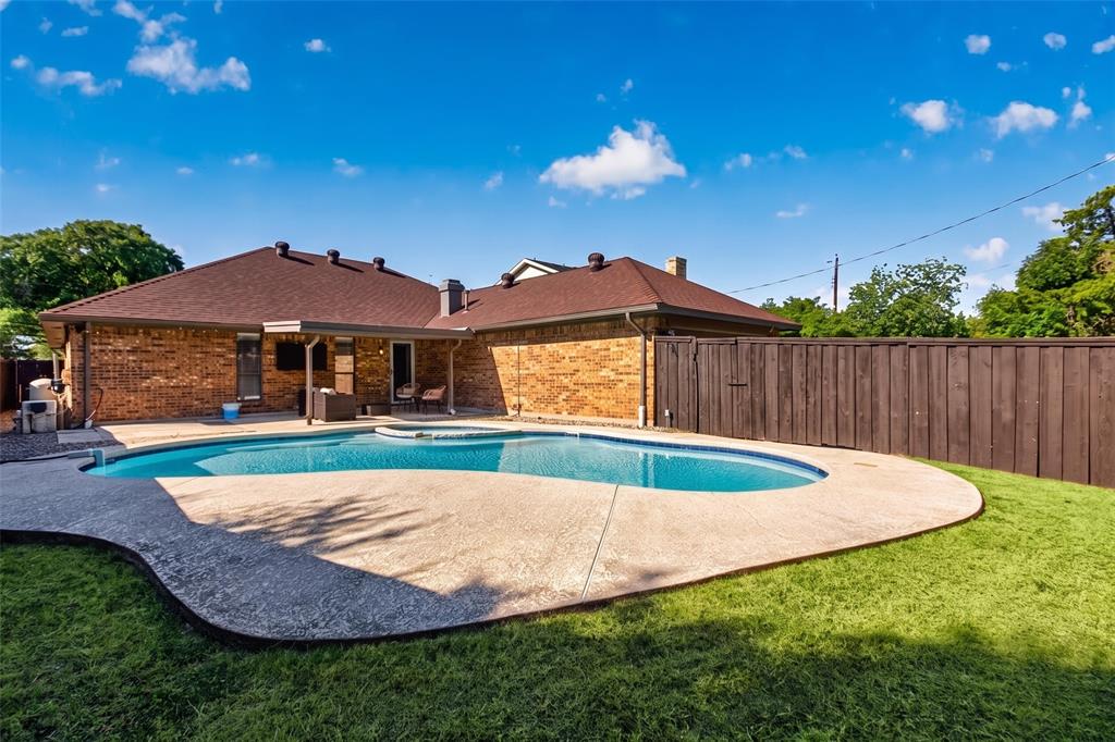 Private backyard featuring a freeform swimming pool, integrated spa, and expansive concrete decking