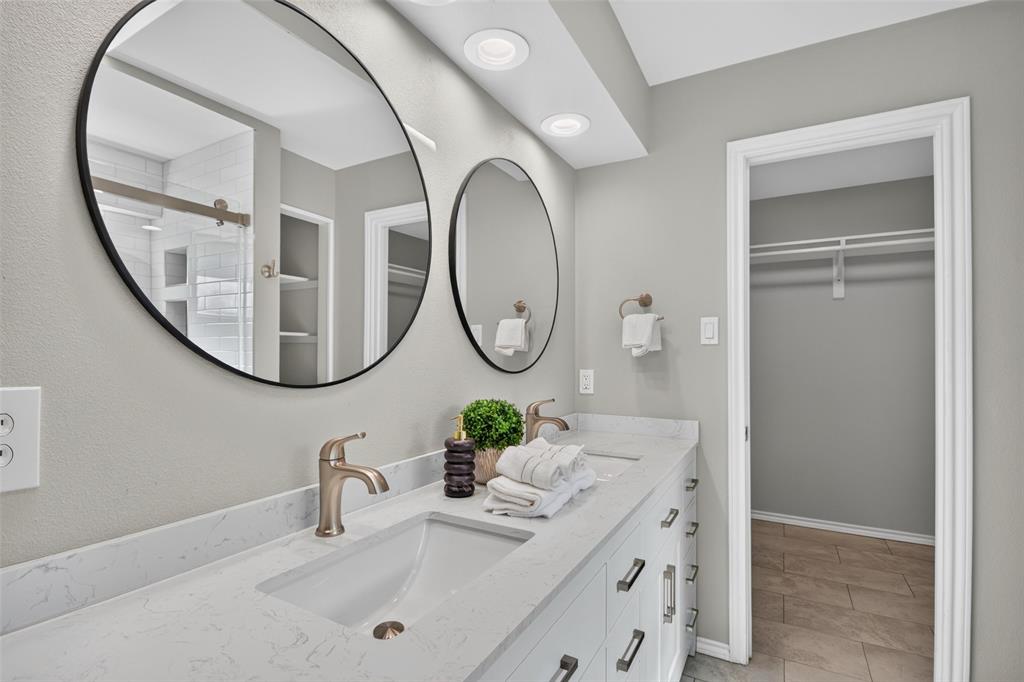 Dual vanity with integrated sinks, brushed bronze fixtures, and round black-framed mirrors