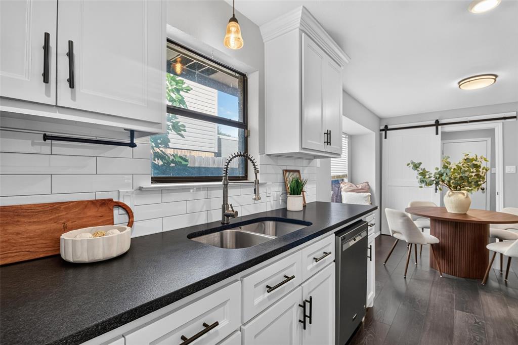 White shaker cabinetry, dark countertops, a subway tile backsplash, a stainless steel sink with a gooseneck faucet, and dark wood-finish flooring