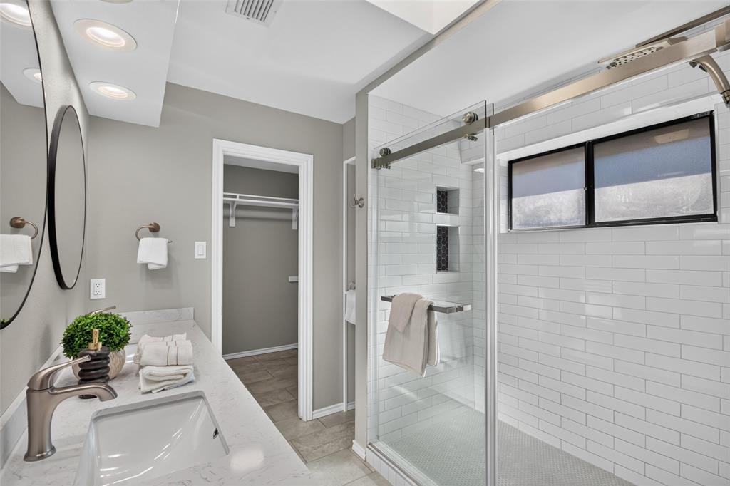 Bathroom featuring a vanity with an undermount sink and a polished chrome faucet, dual circular mirrors, and recessed lighting