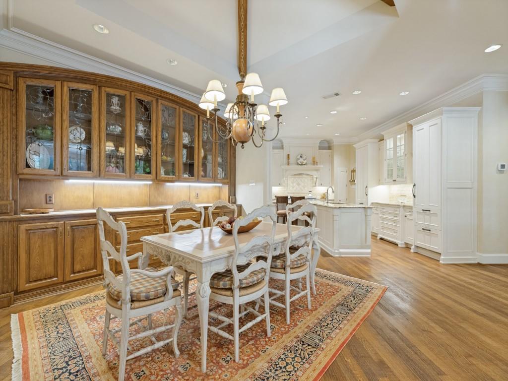 Hardwood flooring throughout, custom wood-finish cabinetry with glass fronts, recessed lighting, crown molding, and a spacious kitchen area with white cabinetry