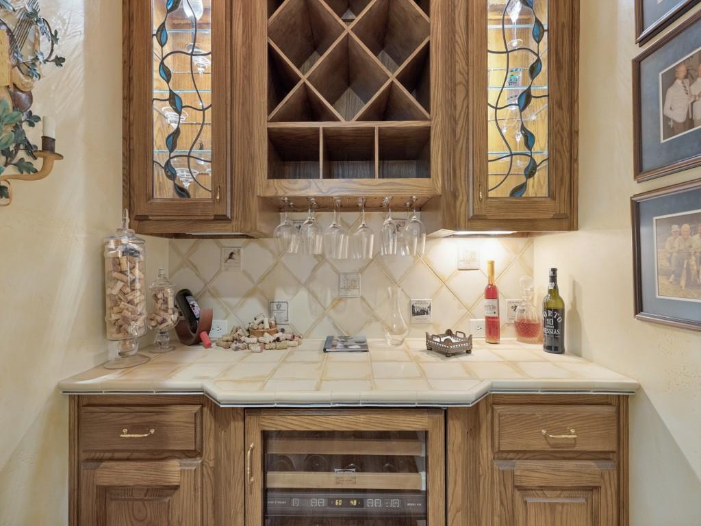 Bar featuring a wine refrigerator, integrated wine rack, tile countertop, and custom cabinetry with leaded glass inserts