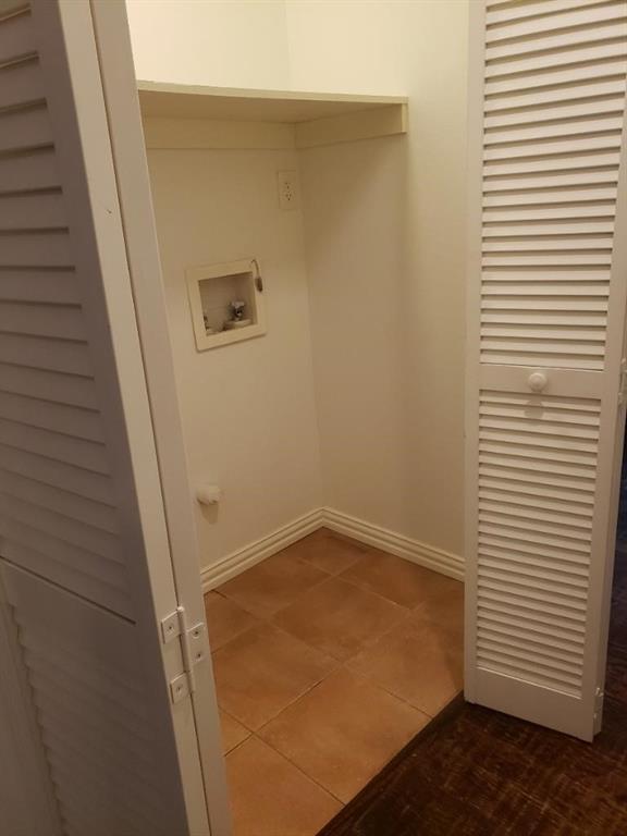 Laundry area featuring a built-in shelf, tile flooring, and louvered bi-fold doors