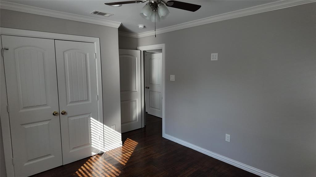 Wood-finish flooring, white crown molding, and a ceiling fan