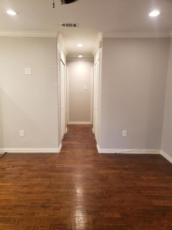 Wood-finish flooring, recessed lighting, crown molding, and two louvered closet doors