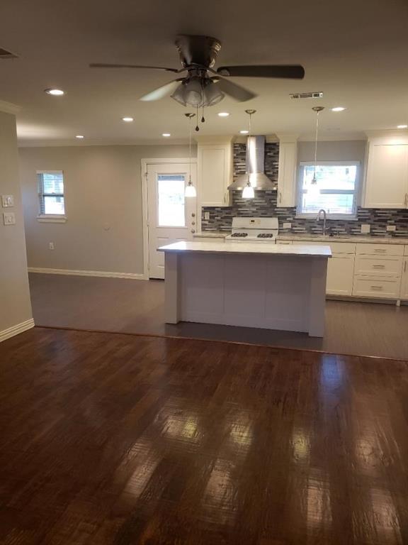 Open-concept kitchen and living area featuring warm wood-finish flooring, recessed ceiling lighting, and a ceiling fan