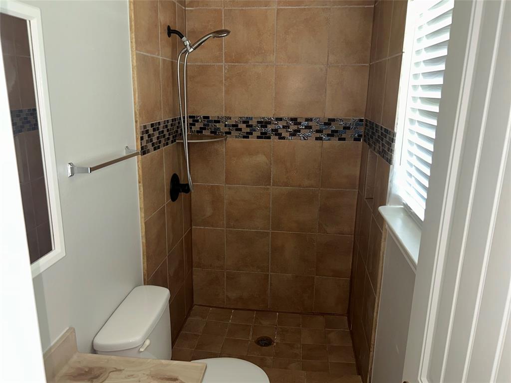Tiled shower stall featuring a decorative mosaic accent band, built-in shelf, and handheld shower fixture Tiled shower stall featuring a decorative mosaic accent band, built-in shelf, and handheld shower fixture