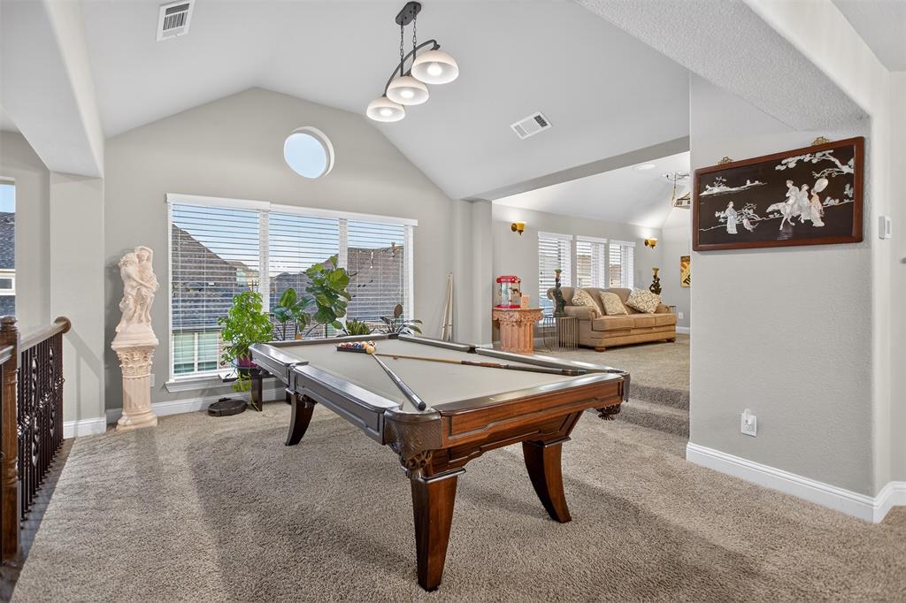 Vaulted ceiling with modern chandelier, round accent window, wall of windows with blinds, and carpeted flooring