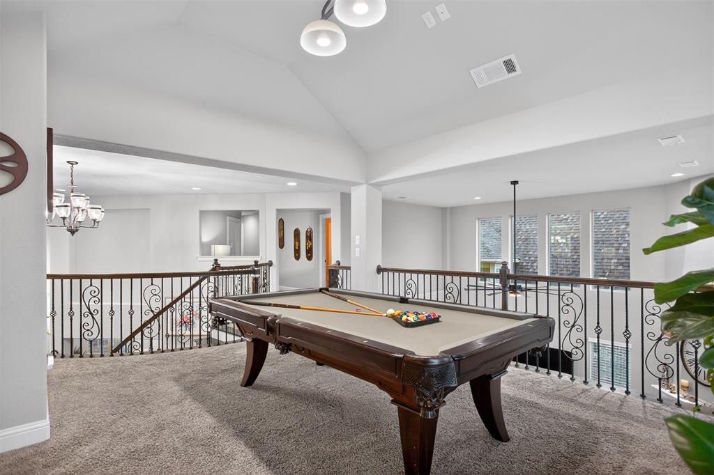 Spacious loft area with vaulted ceilings, recessed lighting, and ornate wrought iron railings