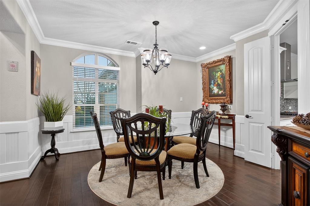 Hardwood flooring, arched window, paneled wainscoting, crown molding, and chandelier lighting Hardwood flooring, arched window, paneled wainscoting, crown molding, and chandelier lighting