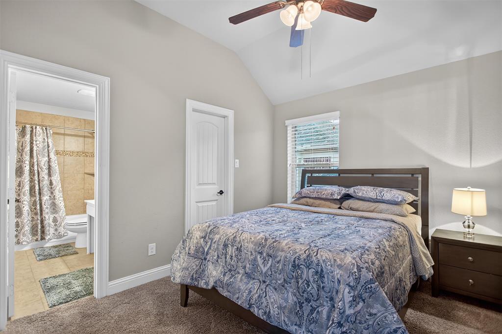 Vaulted ceiling with a ceiling fan, carpeted flooring, and a bedroom door with paneling