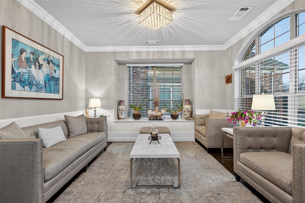 Living area featuring a crystal chandelier, crown molding, arched windows, and wainscoting Living area featuring a crystal chandelier, crown molding, arched windows, and wainscoting