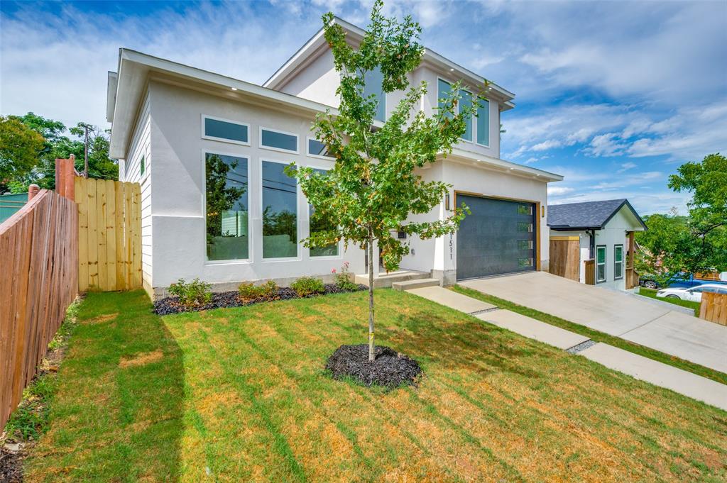 White stucco exterior with a flat roofline, an integrated garage, a concrete driveway, a manicured lawn, and a wooden privacy fence