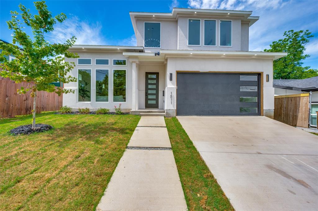 Contemporary stucco exterior with a flat roofline, oversized windows, a modern garage door, and a concrete walkway with integrated lawn strips