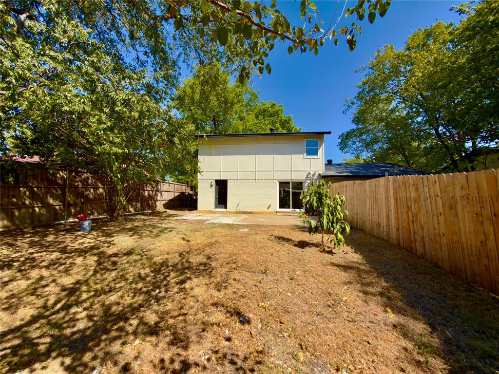 Expansive yard with mature trees, offering privacy with full wood fencing