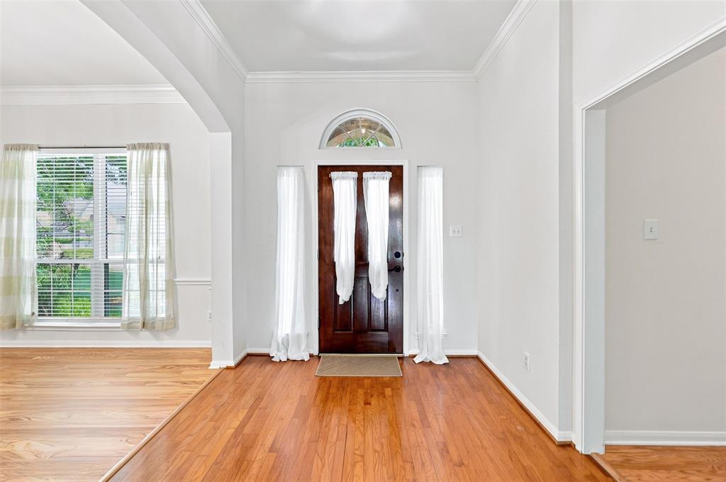 Entryway featuring wood-finish flooring, a wood paneled door with an arched transom, and white wall finishes.