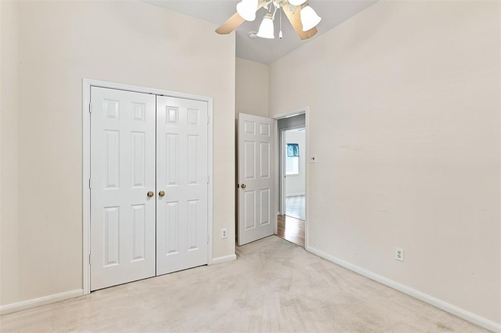 Vaulted ceiling with a ceiling fan, white paneled bifold closet doors, and light-colored wall-to-wall carpeting