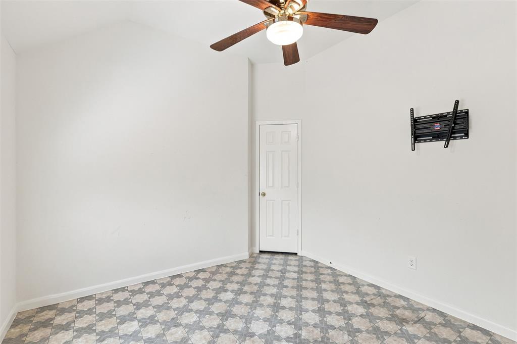 Fourth bedroom with patterned vinyl flooring and TV mount with large walk-in closet.