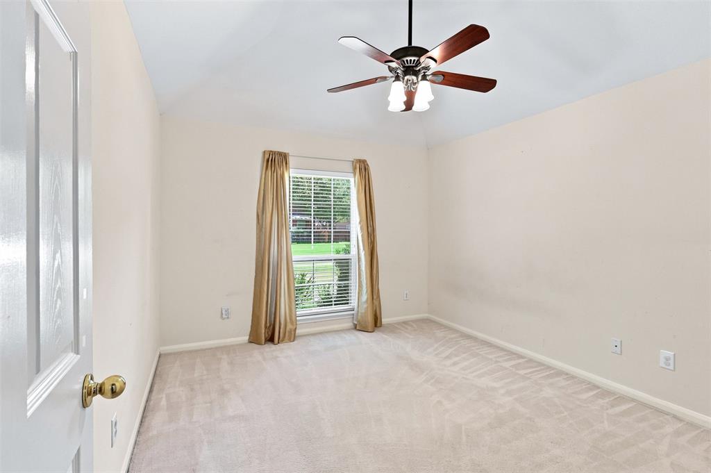 Third bedroom with vaulted ceiling, window looking to front of home and neutral carpet.