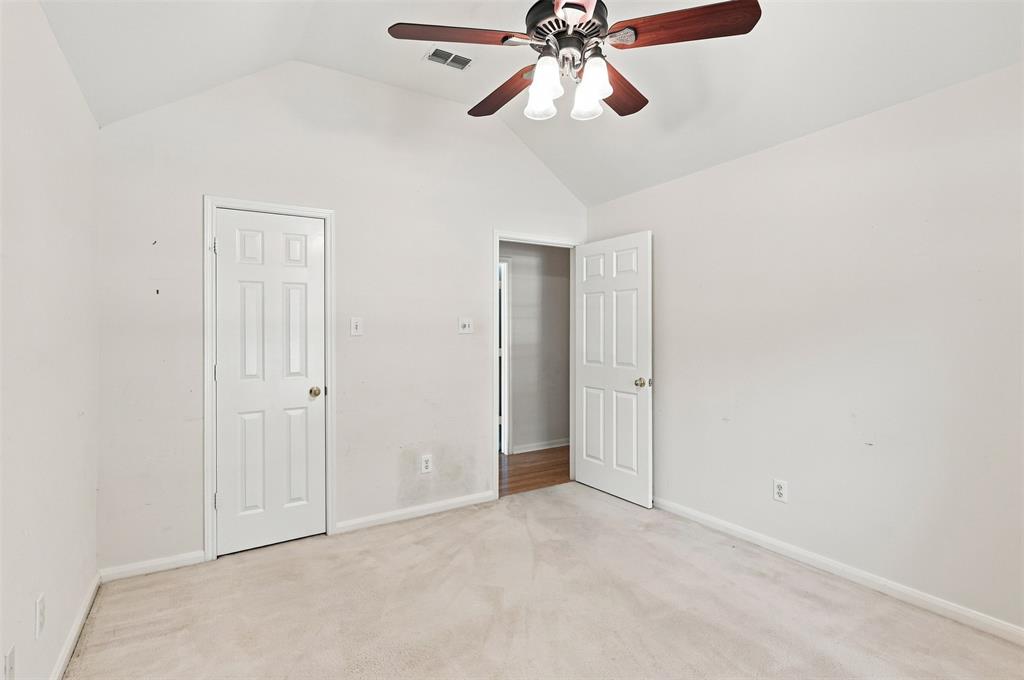 Vaulted ceiling, ceiling fan with integrated lighting, paneled interior doors, and carpet flooring