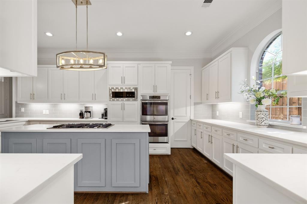 White quartz counters, custom cabinetry with spice storage, double ovens, built-in microwave.