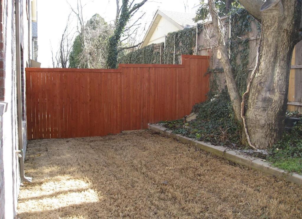 Private backyard area featuring a wood fence, mature tree, and concrete curbing Private backyard area featuring a wood fence, mature tree, and concrete curbing