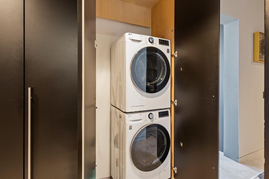 Built-in laundry closet with stacked appliances and dark paneled doors