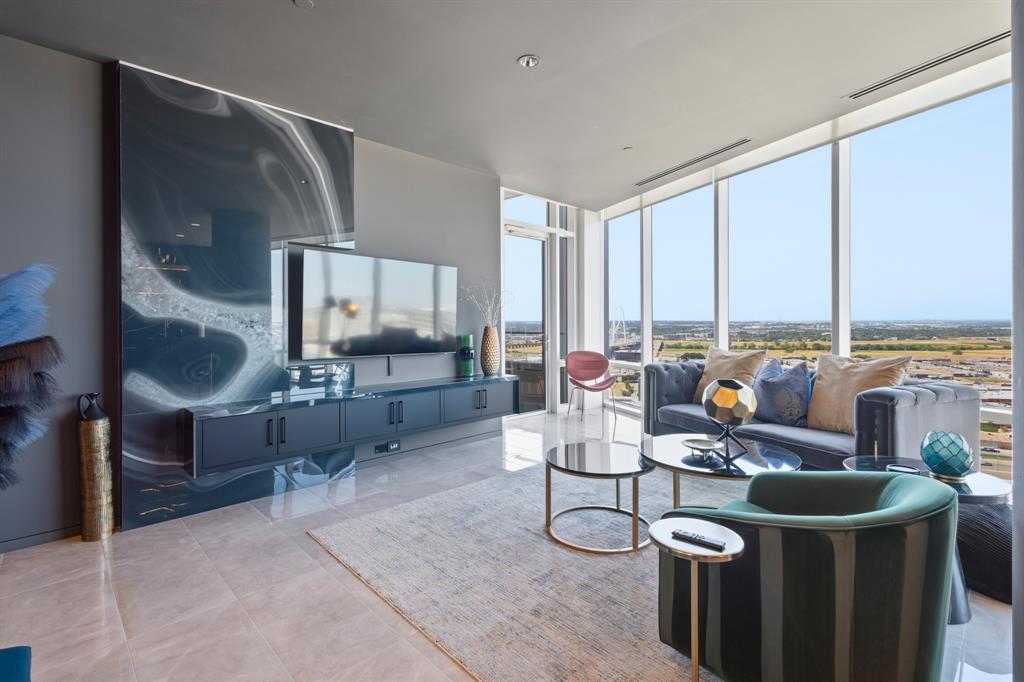 Expansive floor-to-ceiling windows, large format tile flooring, a wall-mounted media console, and a striking accent wall Expansive floor-to-ceiling windows, large format tile flooring, a wall-mounted media console, and a striking accent wall