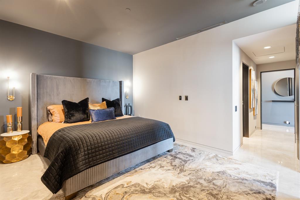 Accent wall with sconce lighting, sleek wall-mounted outlets, overhead recessed lighting, and polished stone tile flooring