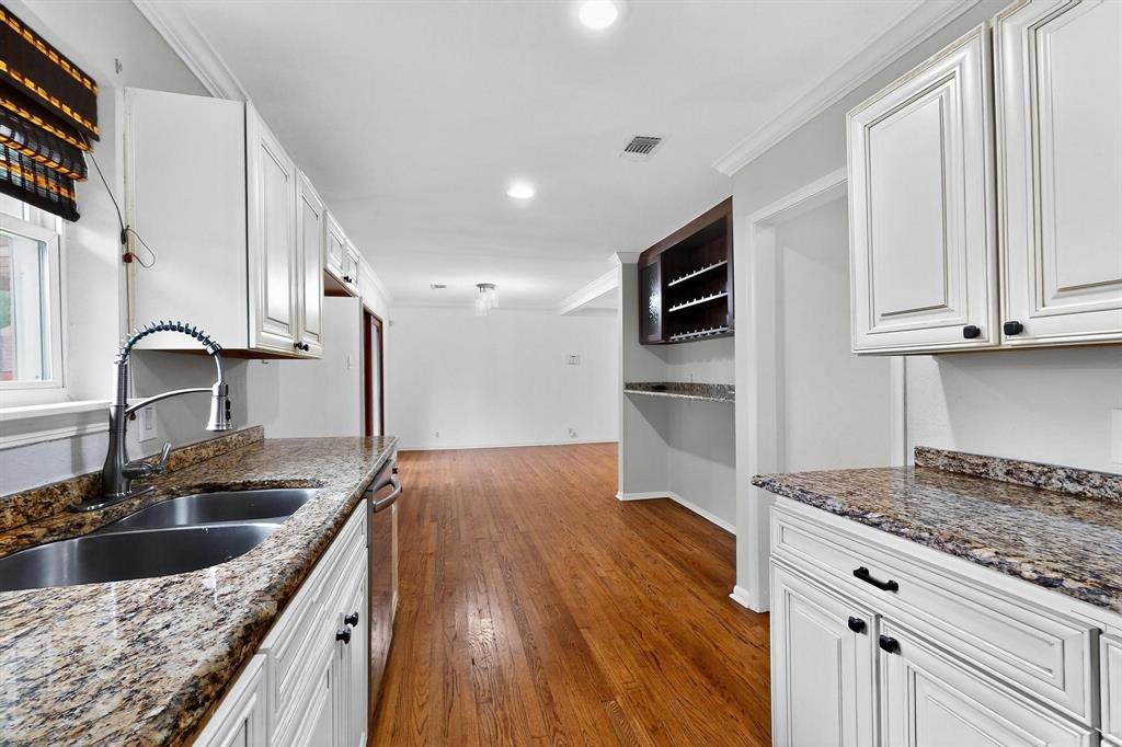 Kitchen with wood finished floors, crown molding, white cabinets, dark stone counters, and recessed lighting Kitchen with wood finished floors, crown molding, white cabinets, dark stone counters, and recessed lighting