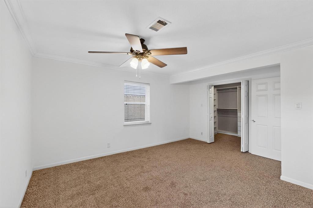 Unfurnished bedroom featuring ornamental molding, carpet flooring, ceiling fan, a walk in closet, and a closet
