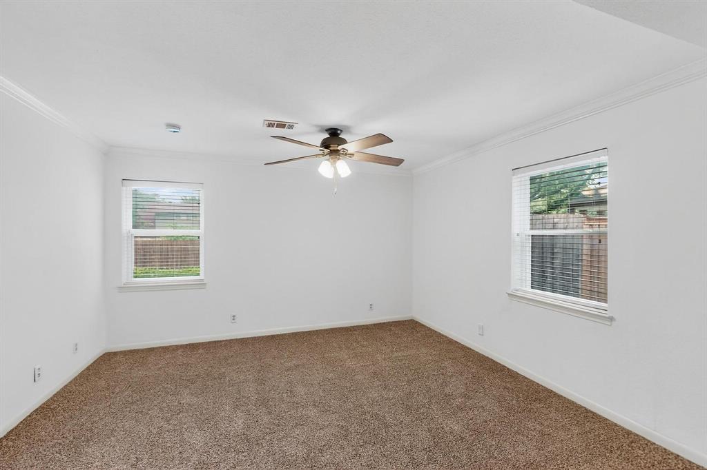 Carpeted spare room with crown molding, healthy amount of natural light, a ceiling fan, and a smoke detector