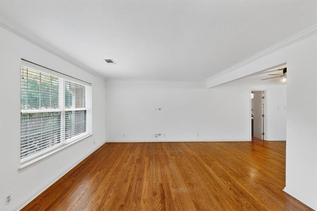 Empty room with ornamental molding, wood finished floors, and ceiling fan Empty room with ornamental molding, wood finished floors, and ceiling fan