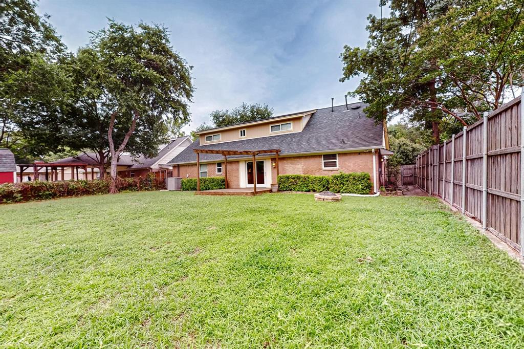 Back of property featuring a fenced backyard, a pergola, and a shingled roof