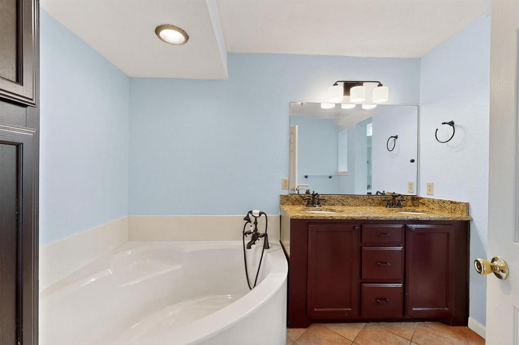 Full bath featuring tile patterned floors, a garden tub, and double vanity