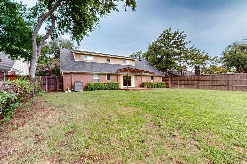 Rear view of house featuring a pergola, a fenced backyard, brick siding, roof with shingles, and a patio