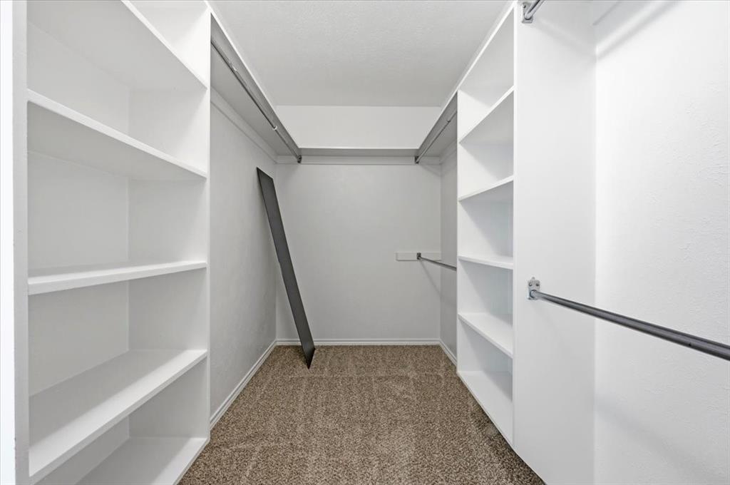 Primary bedroom closetwith shelves and rods