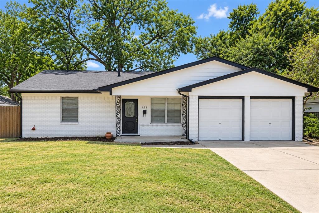 White brick exterior with black trim, a dark asphalt shingle roof, and a two-car garage