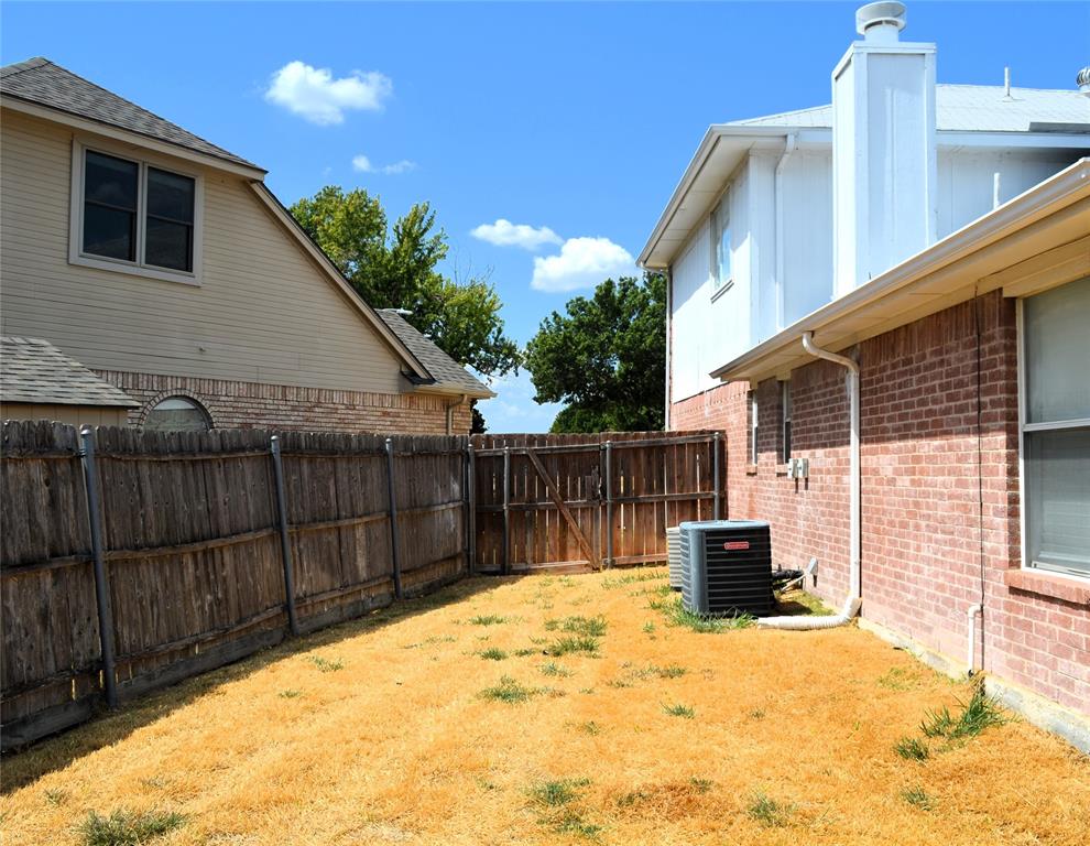 Brick exterior with white trim, wood privacy fence, and an outdoor HVAC unit