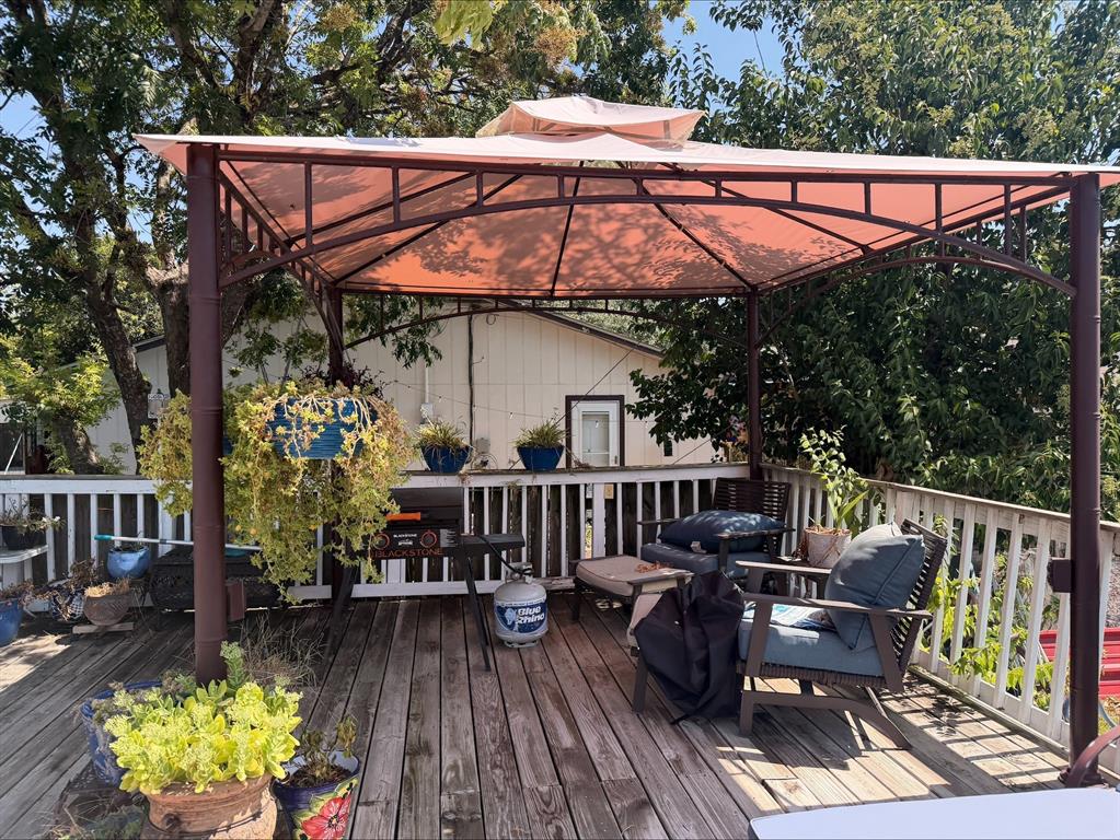 Outdoor wooden deck featuring a gazebo with a fabric canopy