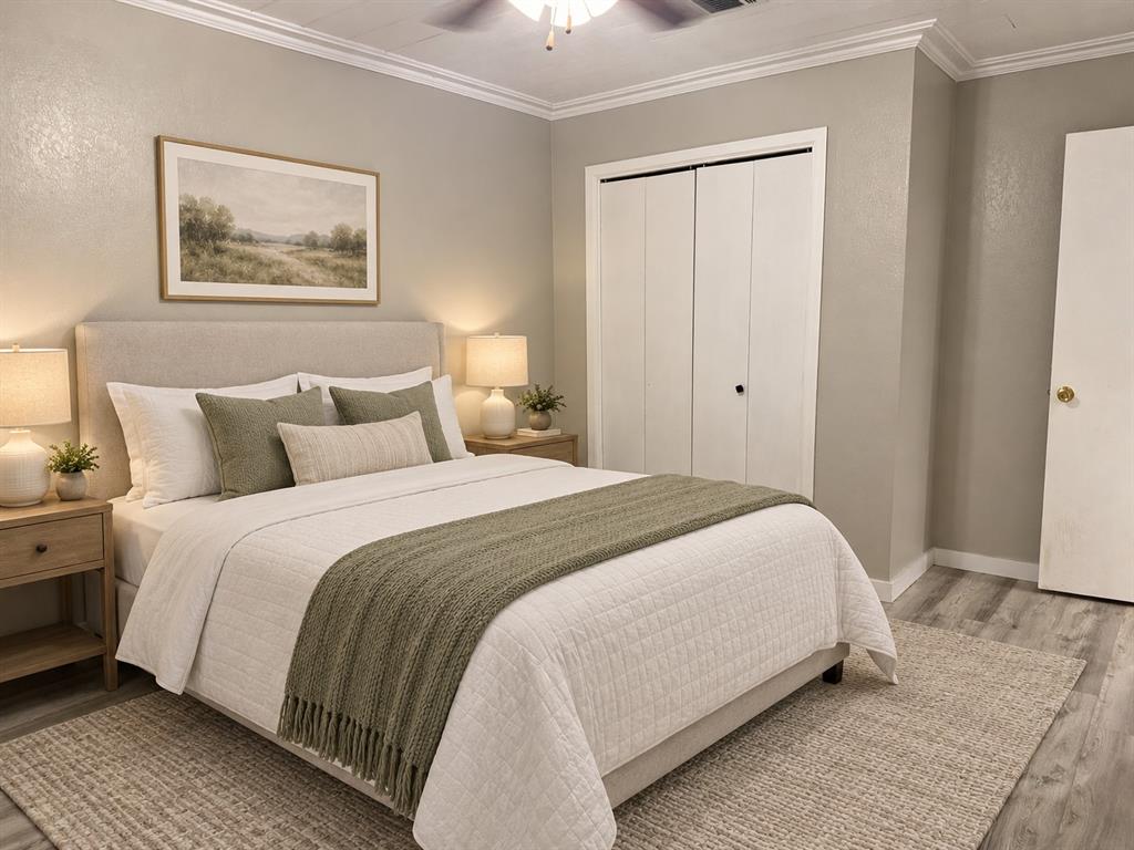 Wood-finish flooring with a ceiling fan, crown molding, and bi-fold closet doors